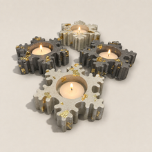 Load image into Gallery viewer, Four gear-shaped concrete tealight candle holders with embedded gold foil flakes, shown lit on a light gray background.
