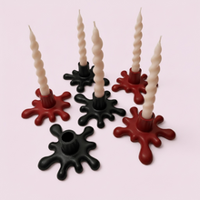 Load image into Gallery viewer, Six twisted spiral taper candles in cream, black, and dark red, each mounted in a matching drip-style holder, arranged on a pale pink background.
