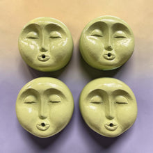 Load image into Gallery viewer, Four round, light yellow-green decorative face ornaments with closed eyes and small mouth holes, arranged in a 2x2 grid on a pastel gradient background.
